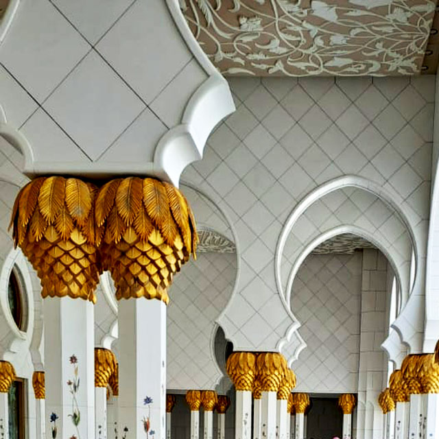 Close-up view of ornately decorated pillars inside the Sheikh Zayed Grand Mosque, showcasing exquisite floral patterns and craftsmanship.