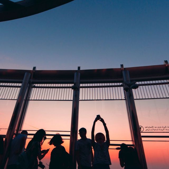 Thrilled visitors posing on the iconic Burj Khalifa balcony, taking in stunning Dubai skyline