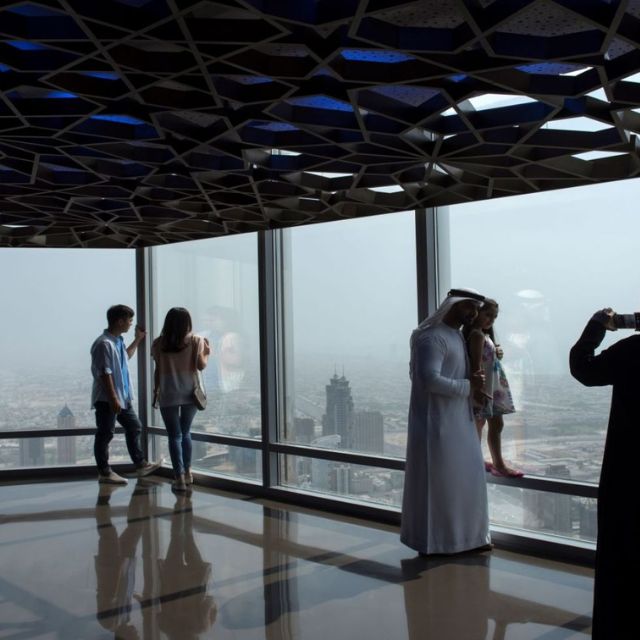 Happy families capturing unforgettable moments while enjoying panoramic views of Dubai City from the Burj Khalifa observation deck.