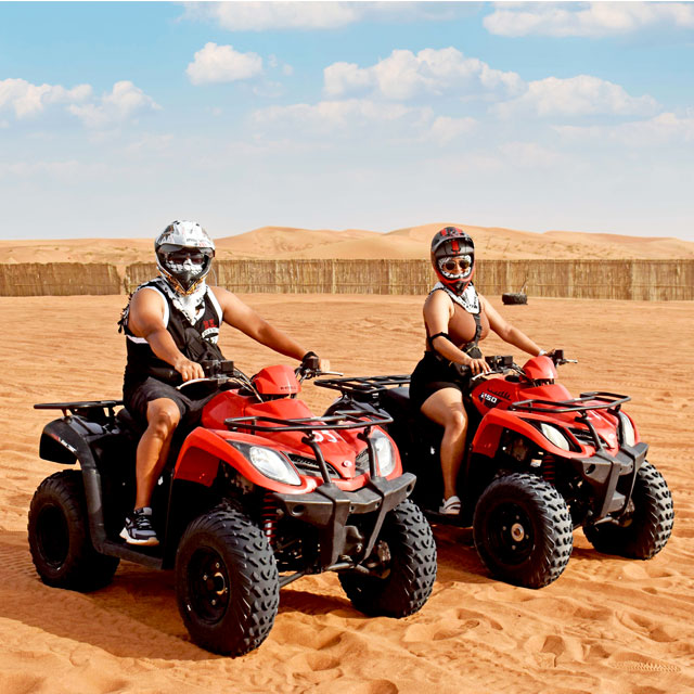Couple enjoying individual quad bike thrills during a Dune Rider Adventure in Dubai.