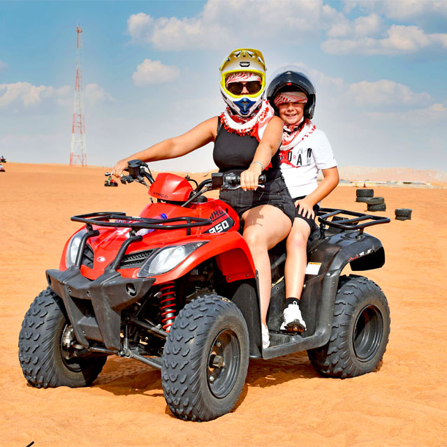Family fun in the dunes: mother and son riding together on an ATV