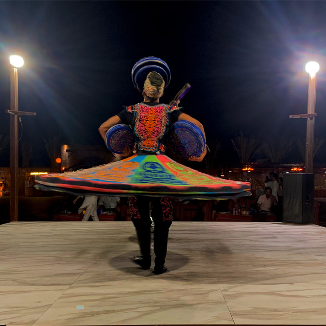 Tanoura dancer spinning on stage during camp activities at Prime Dubai Dunes Safari.