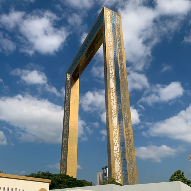 Close-up view of the Dubai Frame's golden facade, a rectangular structure inspired by a picture frame, set against a backdrop of blue sky.