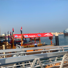 Abra water taxis docked along the Dubai Creek in the historic district, with a walkway connecting passengers to the boats.
