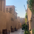 Alleyway in Dubai's Al Fahidi Historical Neighbourhood, showcasing traditional wind towers, old drainage systems, and shady benches.