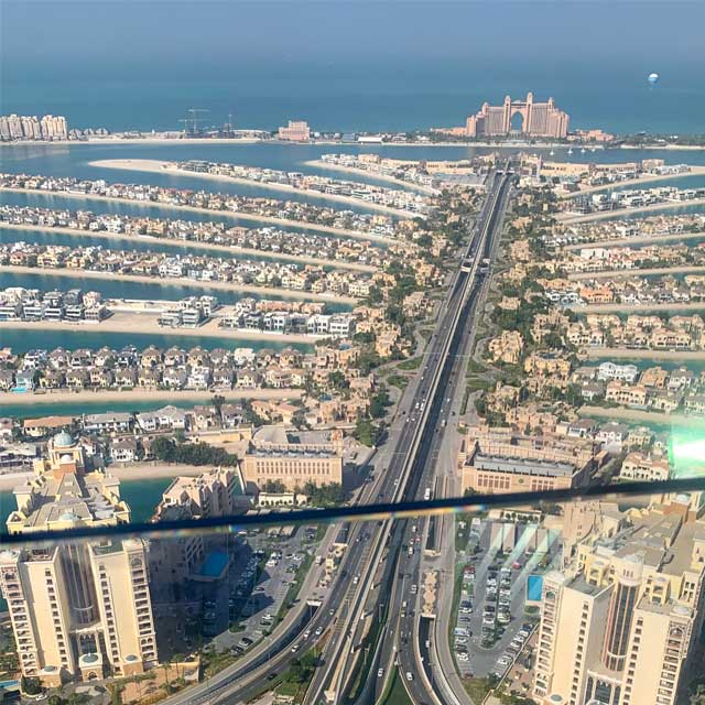 Bird's-eye view of Palm Jumeirah, Dubai's iconic artificial island, showcasing its palm shape and the luxurious Atlantis The Palm hotel at its center.