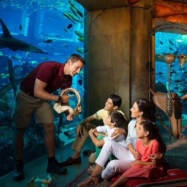 Learning together: A family discovering the wonders of the ocean with the help of a knowledgeable staff member.