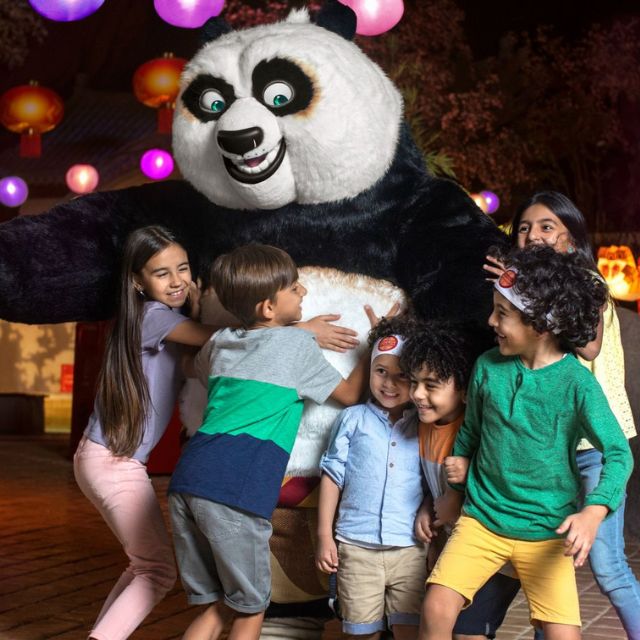 Adorable kids embracing the lovable Po the Panda mascot at Motiongate Dubai