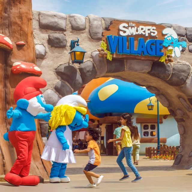Excited kids rushing to meet Papa Smurf and Smurfette in the enchanting Smurf Village at Motiongate Dubai