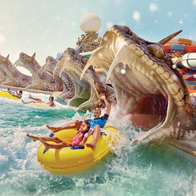 Thrilling water adventure: Father and daughter exiting the snake's mouth on Slither's Slides at Yas Waterworld Abu Dhabi