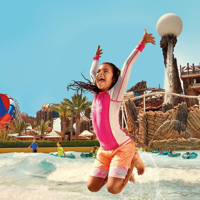 Thrilling wave experience: Girl jumping high on Amwaj Wave Pool at Yas Waterworld Abu Dhabi